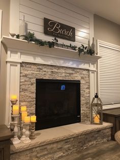 the fireplace is decorated with candles and greenery