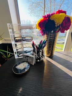 a vase filled with flowers sitting on top of a wooden table next to a window