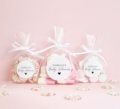 three bags filled with cookies and marshmallows on top of a pink surface