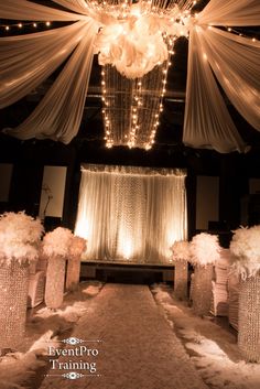 an aisle decorated with white flowers and lights