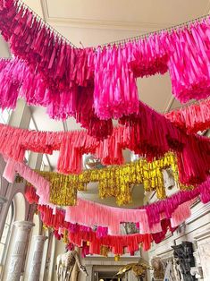 pink and yellow streamers hang from the ceiling in a room filled with statues, sculptures and windows