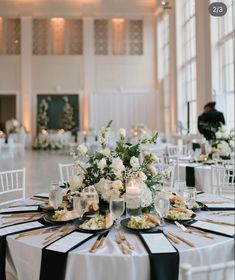 the tables are set up with black and white linens, silverware, and flowers