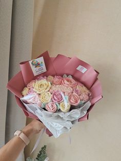 someone is holding a bouquet of roses in pink and white paper with tags on them