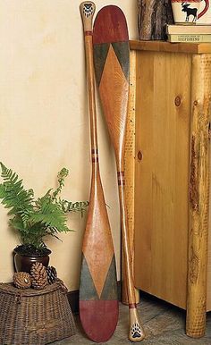 two wooden paddles sitting on top of a floor next to a cabinet and potted plant