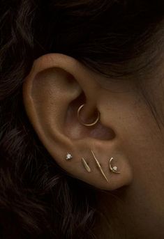 a woman's ear with three different piercings