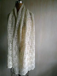 a white knitted shawl sitting on top of a mannequin head stand