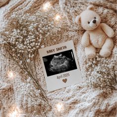 a teddy bear sitting on top of a blanket next to a birth card and baby announcement