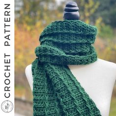 a green knitted scarf sitting on top of a white mannequin