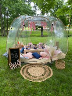 an inflatable bubble tent is set up on the grass with pillows and other items