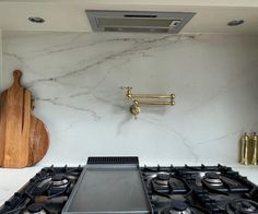 a stove top oven sitting inside of a kitchen next to a cutting board and wooden utensils