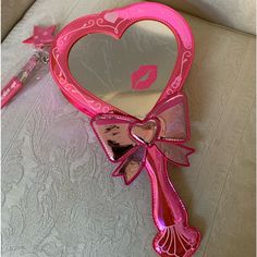 a pink heart shaped mirror sitting on top of a table