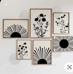 four black and white paintings hanging on the wall above a table with flowers in vases