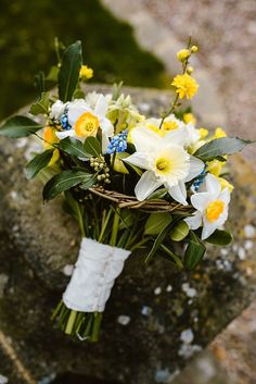 a bouquet of white and yellow flowers sitting on top of a stone slab in the grass