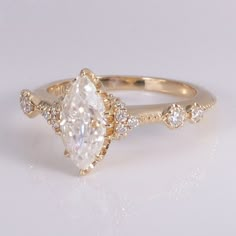 a gold ring with a pear shaped diamond surrounded by small round brilliant cut white diamonds