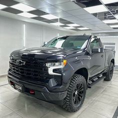 a black truck is parked in a room with white tiles on the floor and ceiling