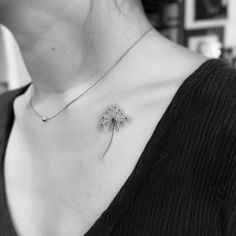 a black and white photo of a dandelion tattoo on a woman's chest