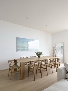 a living room with a couch, table and chairs next to a painting on the wall