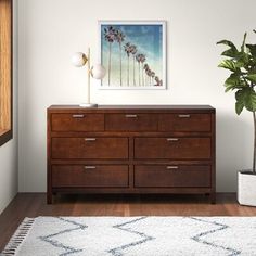 a wooden dresser sitting on top of a hard wood floor next to a potted plant