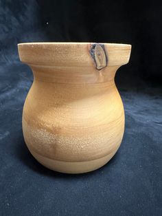 a wooden vase sitting on top of a black surface