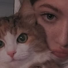 a close up of a person holding a cat in front of their face and looking at the camera