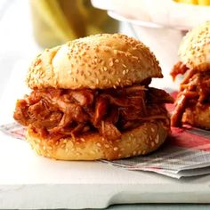 two pulled pork sandwiches sitting on top of a napkin next to some cornbreads