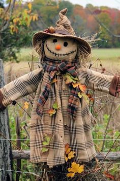 a scarecrow doll sitting on top of a wooden fence next to a pumpkin patch