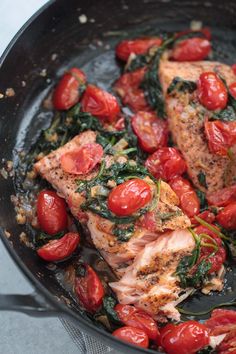 salmon with tomatoes and spinach in a skillet