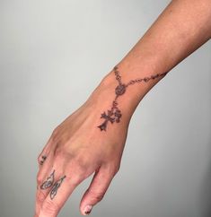 a person's hand with a cross tattoo on it