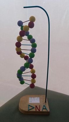 a wooden stand holding a model of a structure with colorful balls on it's sides