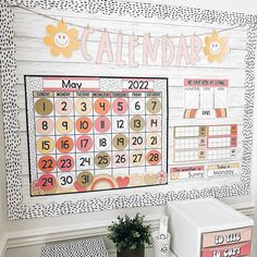 a calendar is hanging on the wall next to a potted plant and two boxes