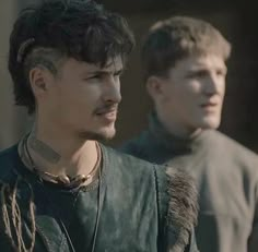 two young men standing next to each other in front of a building and one has tattoos on his face