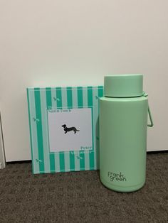 a green insulated water bottle next to a card with a black dog on it