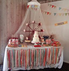 a table topped with lots of candy next to a ferris wheel and sign that says festas