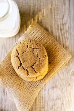 a muffin sitting on top of a burlap bag next to a glass of milk