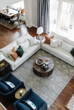 an aerial view of a living room with white couches, blue chairs and coffee table