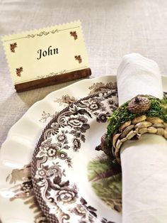 a place setting with napkins and an old - fashioned table name card on it