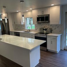 an empty kitchen with white cabinets and stainless steel appliances