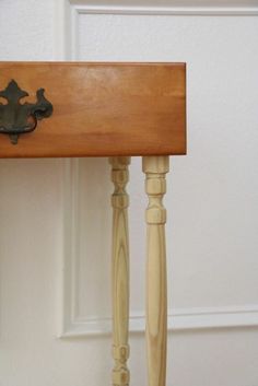 a wooden table with a metal handle on it's top next to a white door