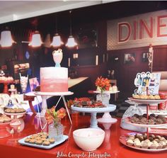 a red table topped with lots of cakes and desserts