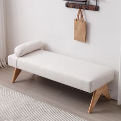 a white bench sitting next to a wall with a bag hanging on it's side