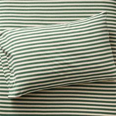 a green and white striped pillow on top of a bed