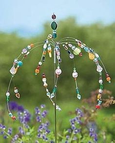 a wind chime in the middle of a field full of purple and green flowers