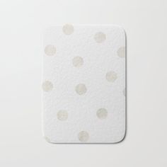 a white and beige polka dot pattern bath mat on a white surface with a gray background