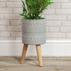 a potted plant sitting on top of a wooden stand next to a brick wall