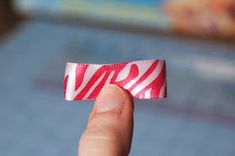 a hand holding a red and white ribbon