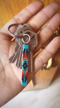 a person is holding a key chain with beads on it