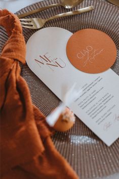 an orange and white place setting with napkins, silverware and utensils