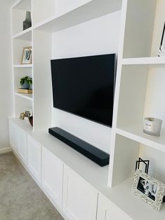 a flat screen tv mounted to the side of a white bookcase in a living room