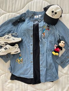 a denim shirt with mickey mouse patches and other items laid out on top of it