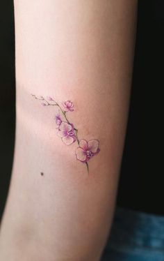 a small pink flower tattoo on the right side of the arm, with purple flowers growing out of it